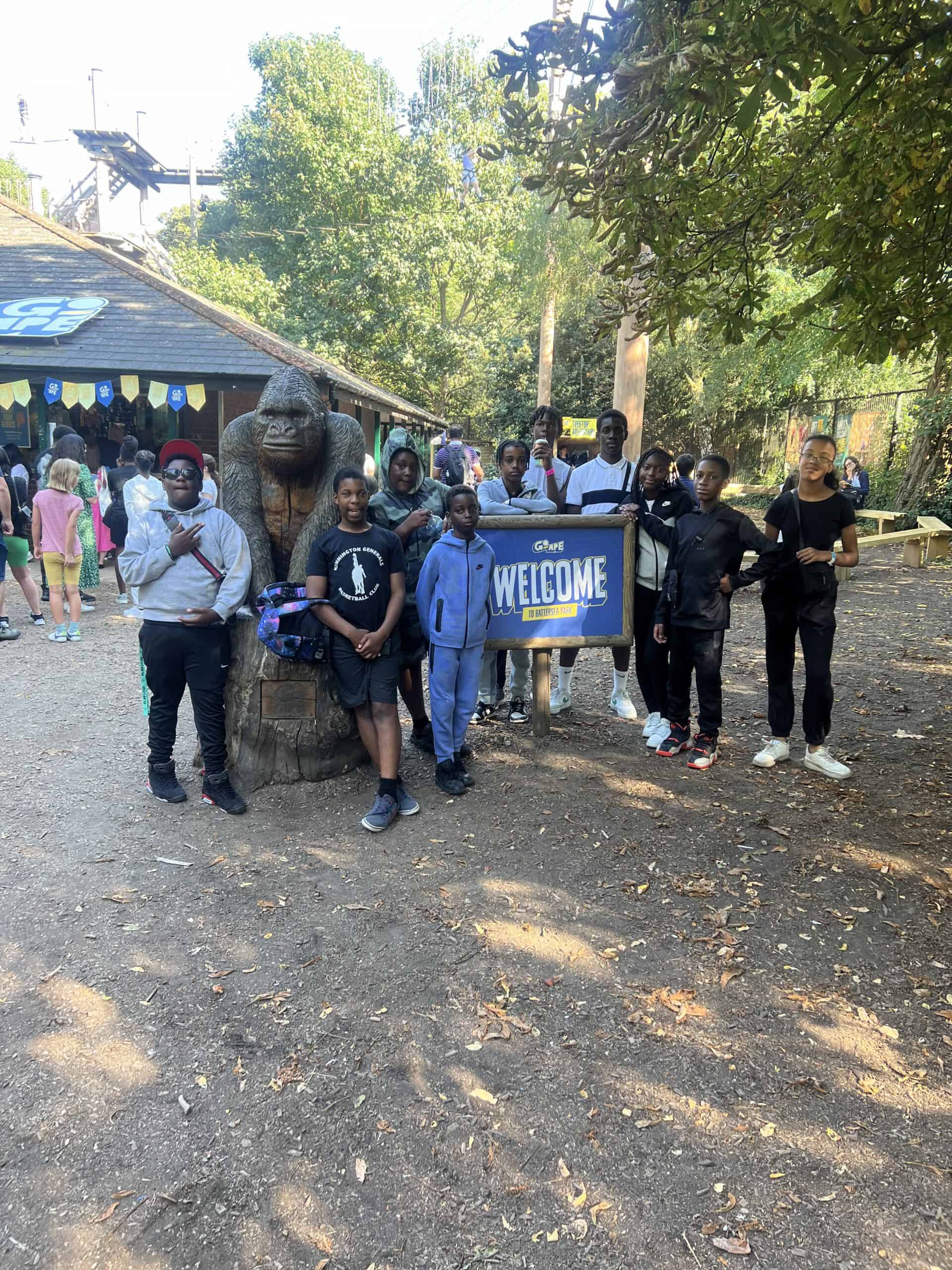 Group of children and adults at C4CWB outdoor event with welcome sign and nature background.
