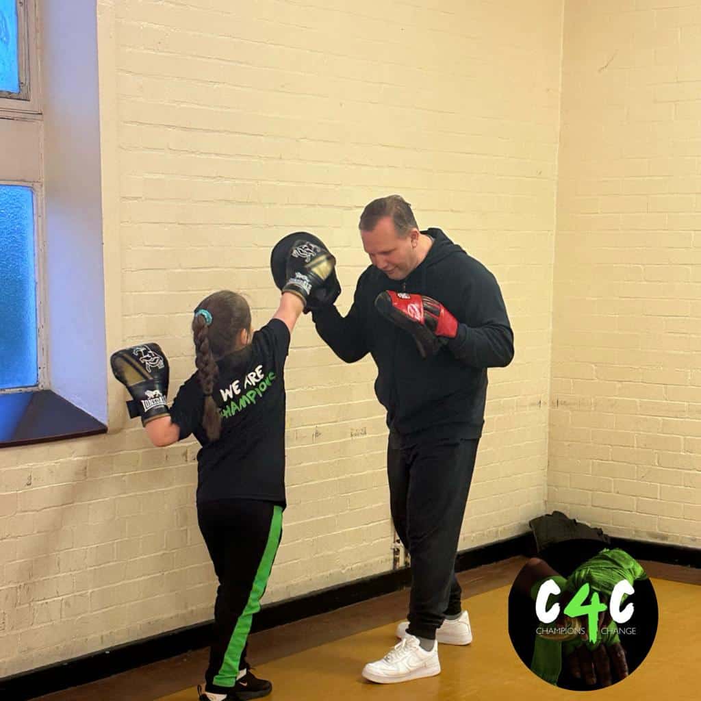 Punching training session between a man and a young girl in a gym.