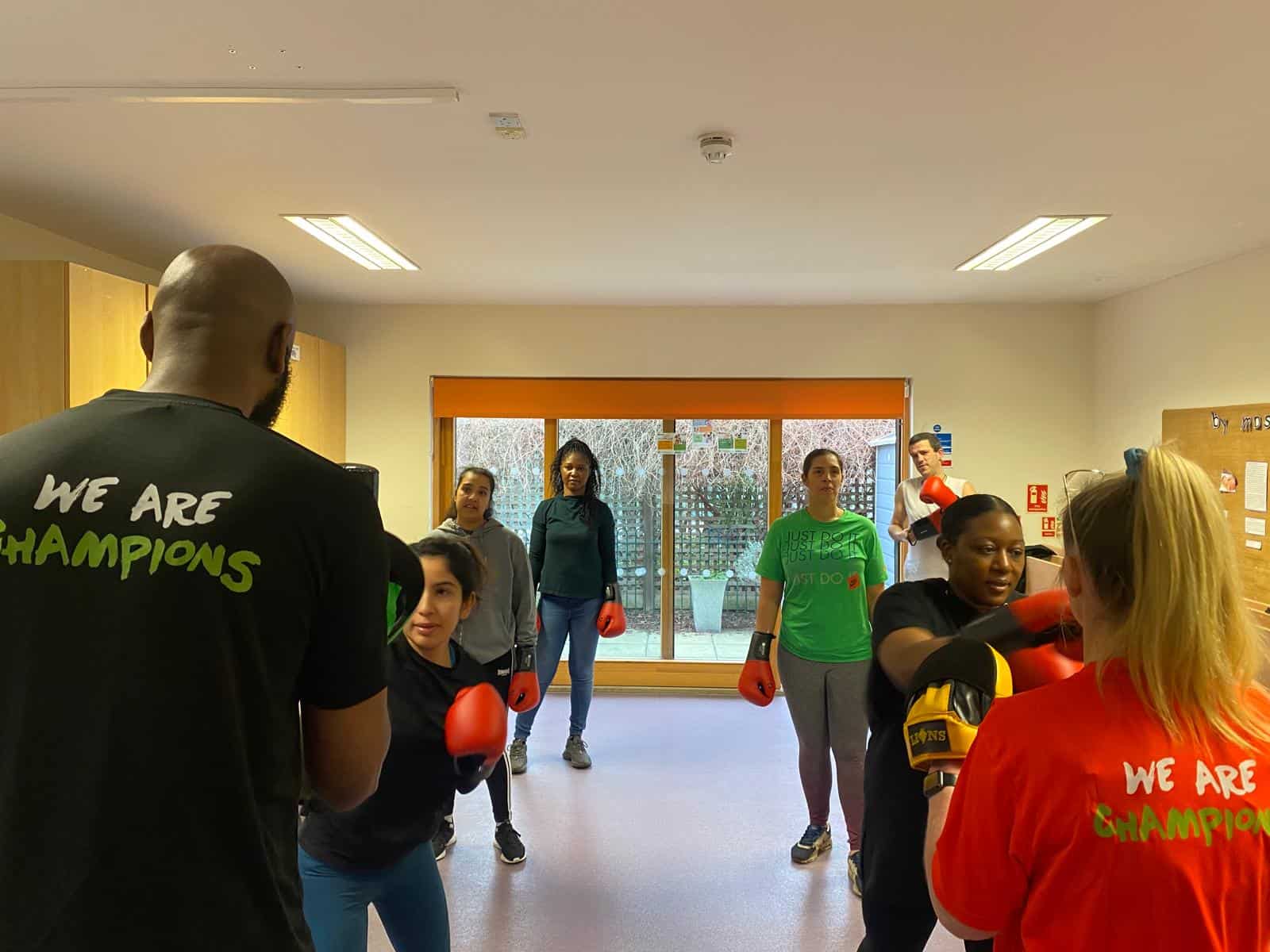 Boxing training session with diverse women in a bright gym, focusing on empowerment and fitness.