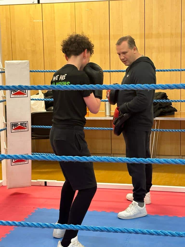 Female boxer training in boxing ring with coach during practice session.