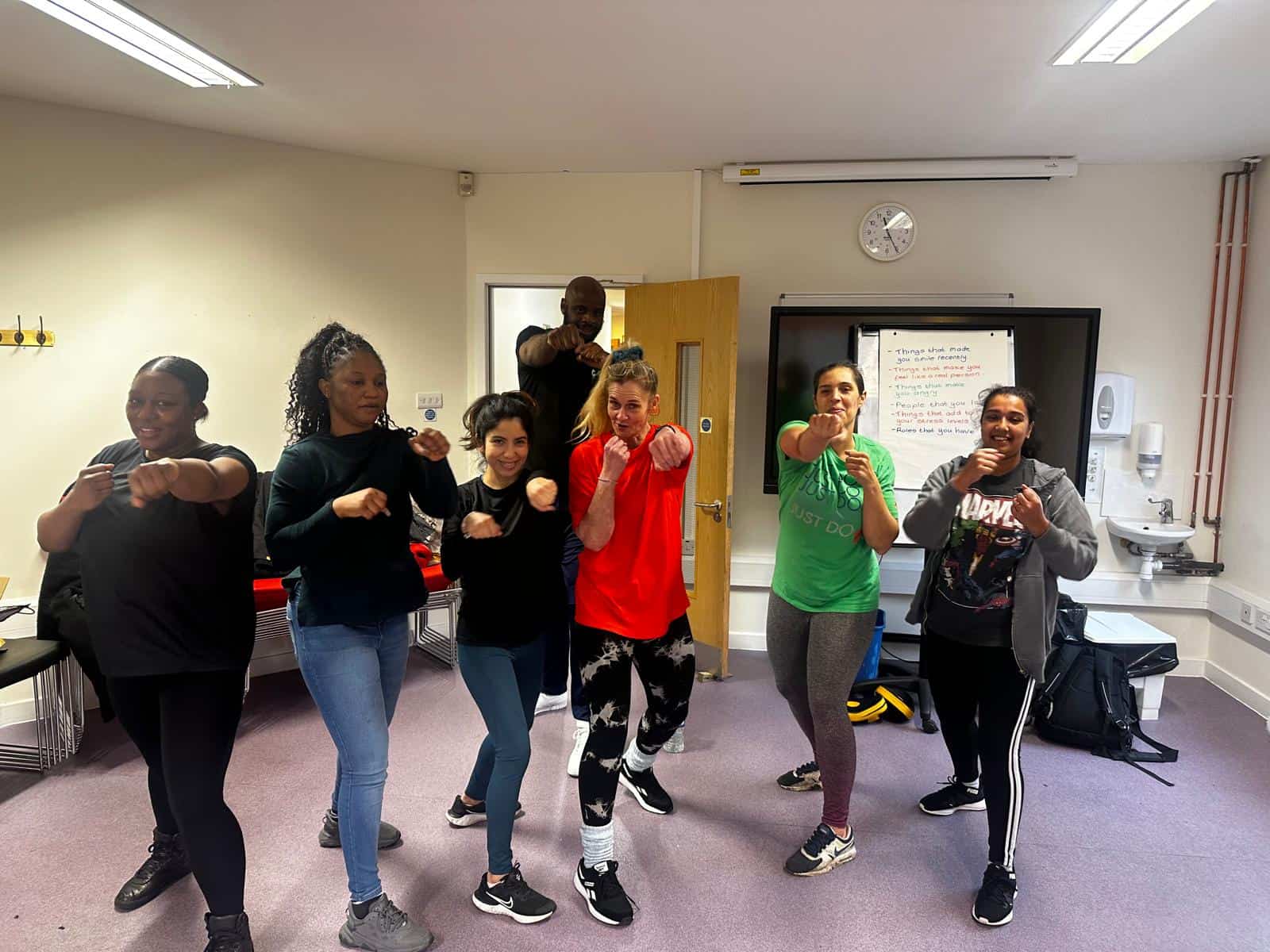 Group of diverse women practicing self-defense in a classroom setting.