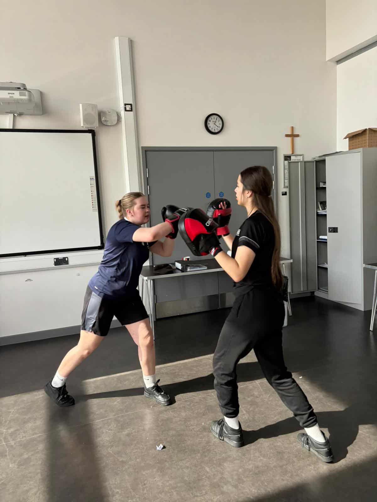Boxing training session between two women in a modern indoor gym.