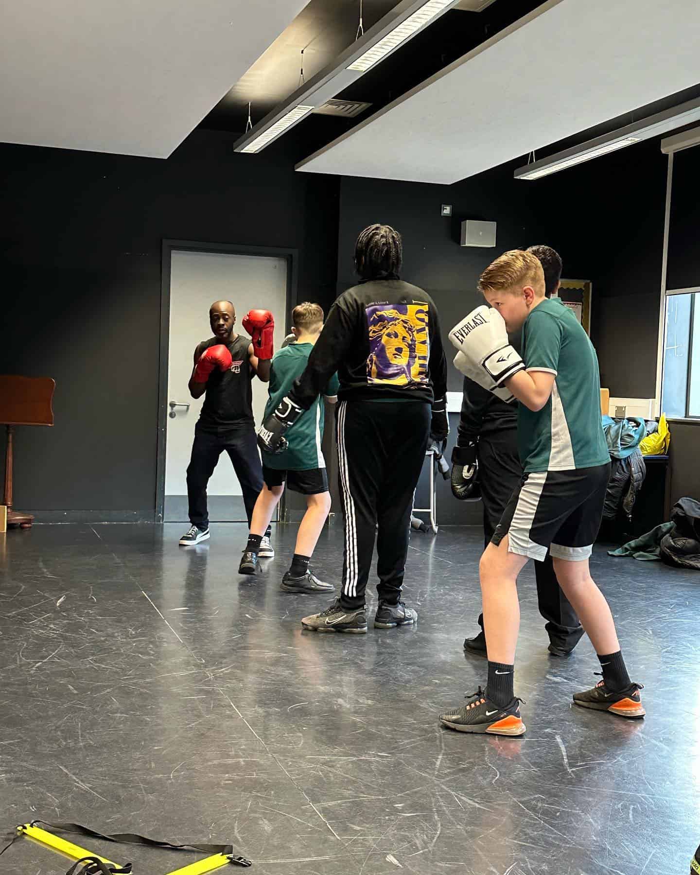 Punching bag boxing training session with young athletes in a modern gym.