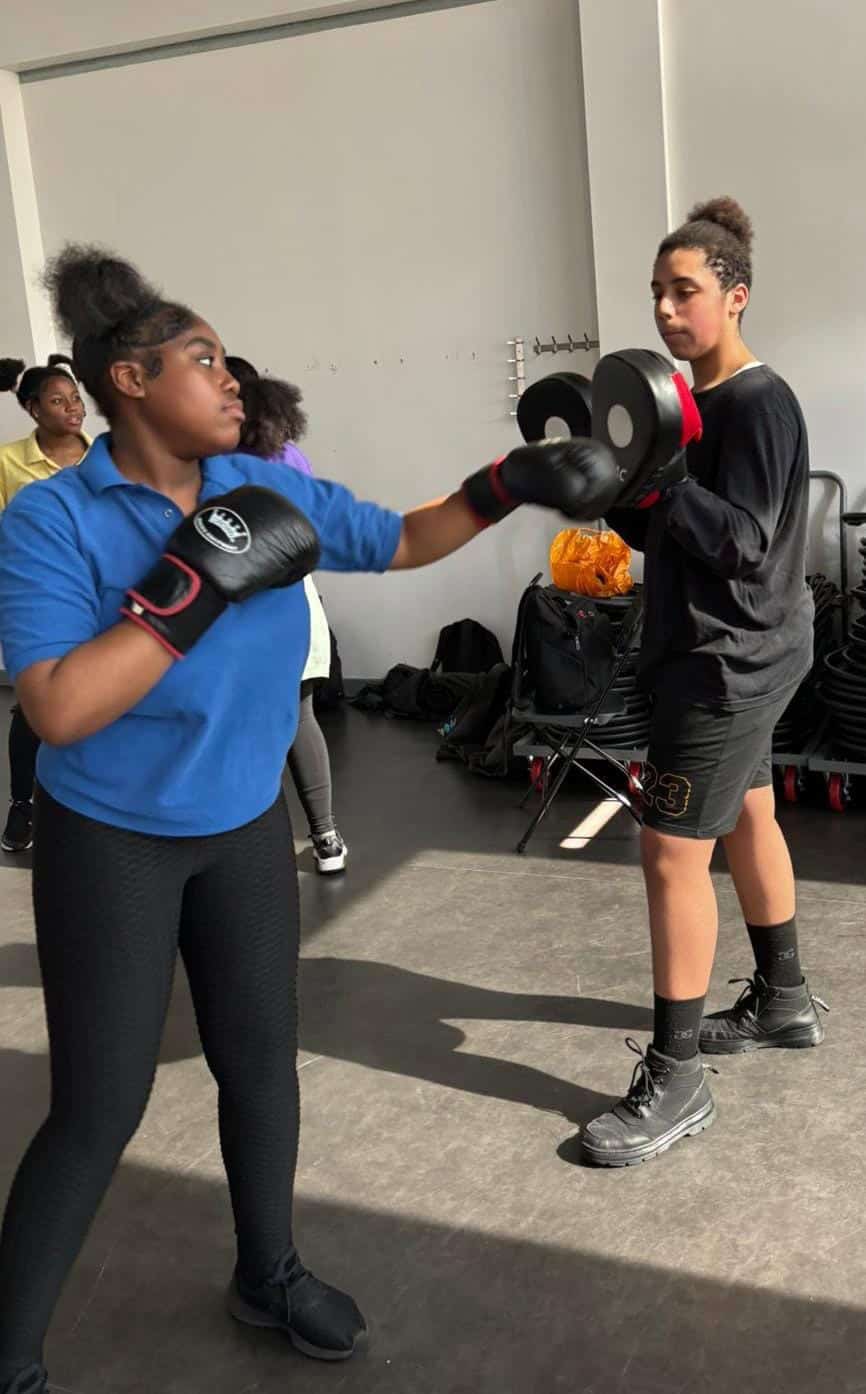 Punching training session with young girls in a fitness class, focusing on boxing skills and self-de.