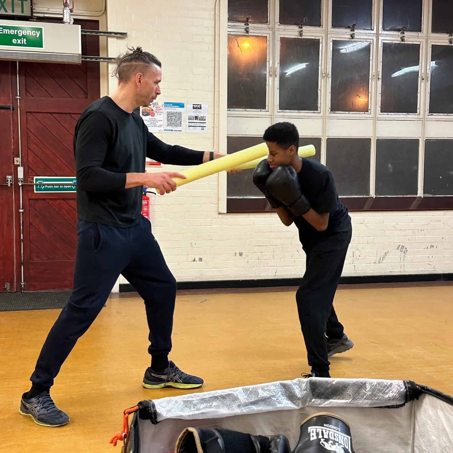Kickboxing training session with instructor and student practicing defensive techniques in a gym.