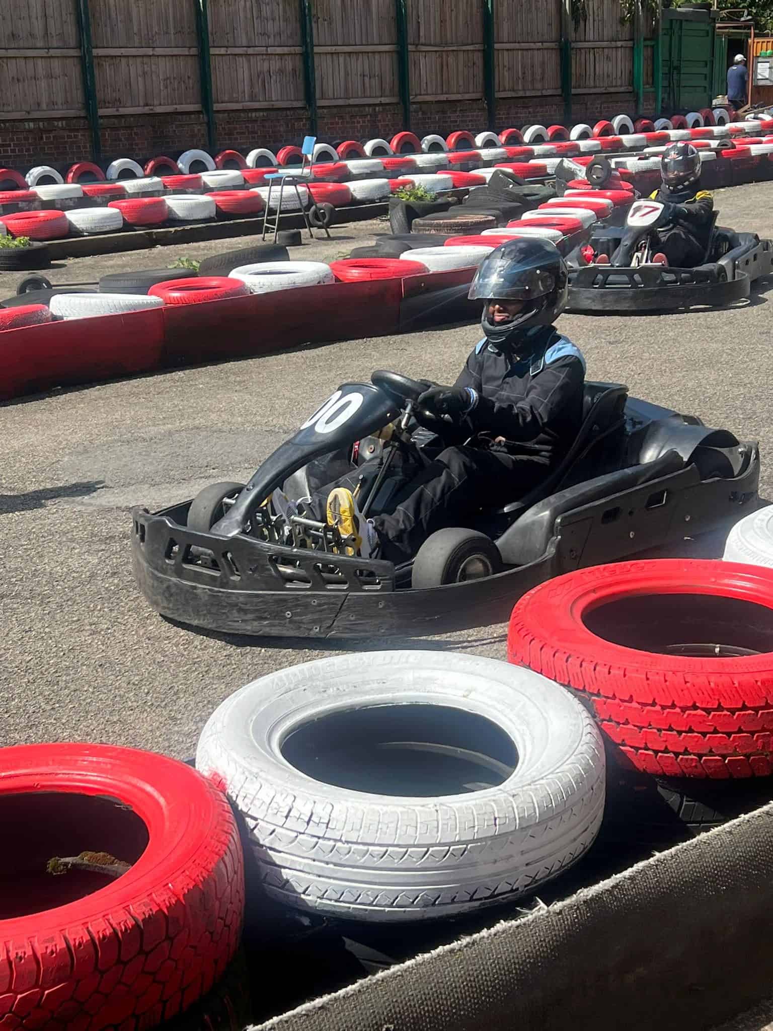 Go-kart racing for kids at an outdoor track with colorful tires and safety gear.