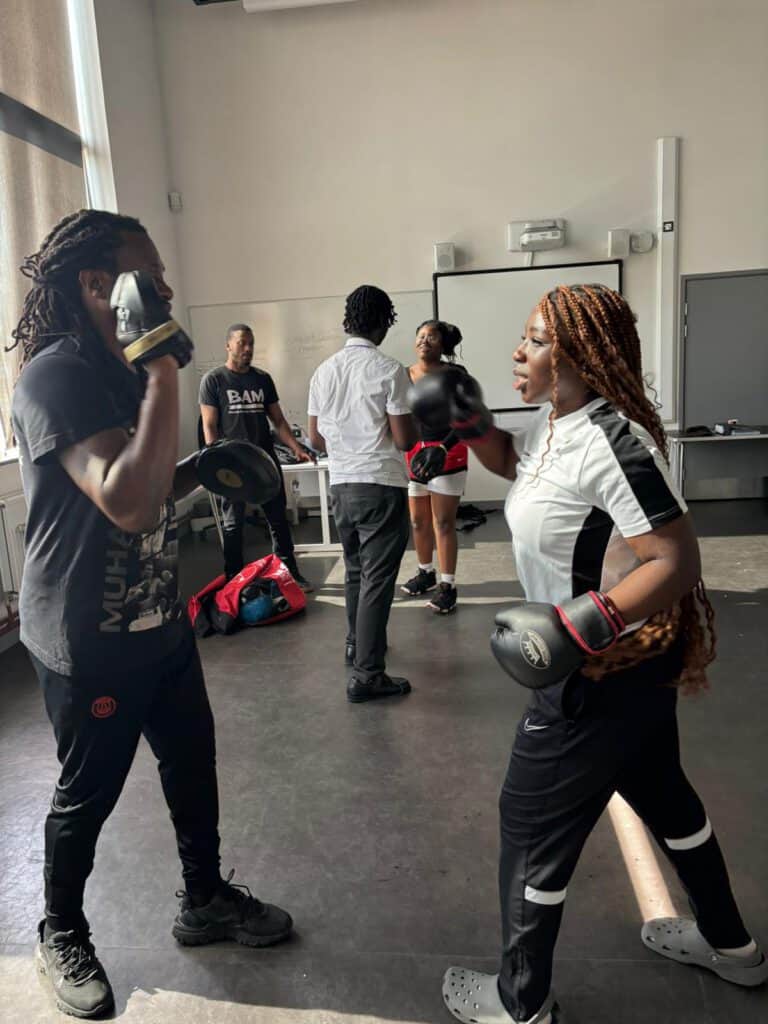 Boxing training session with diverse women in a gym, focusing on fitness and empowerment.