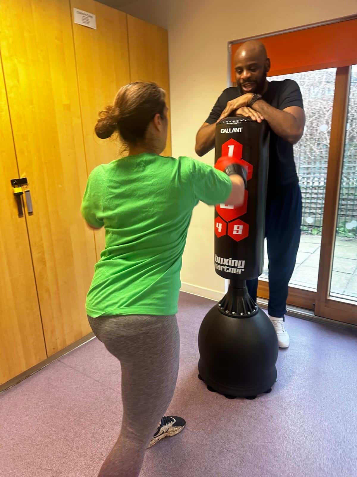 Punching a boxing bag during training session in a gym.