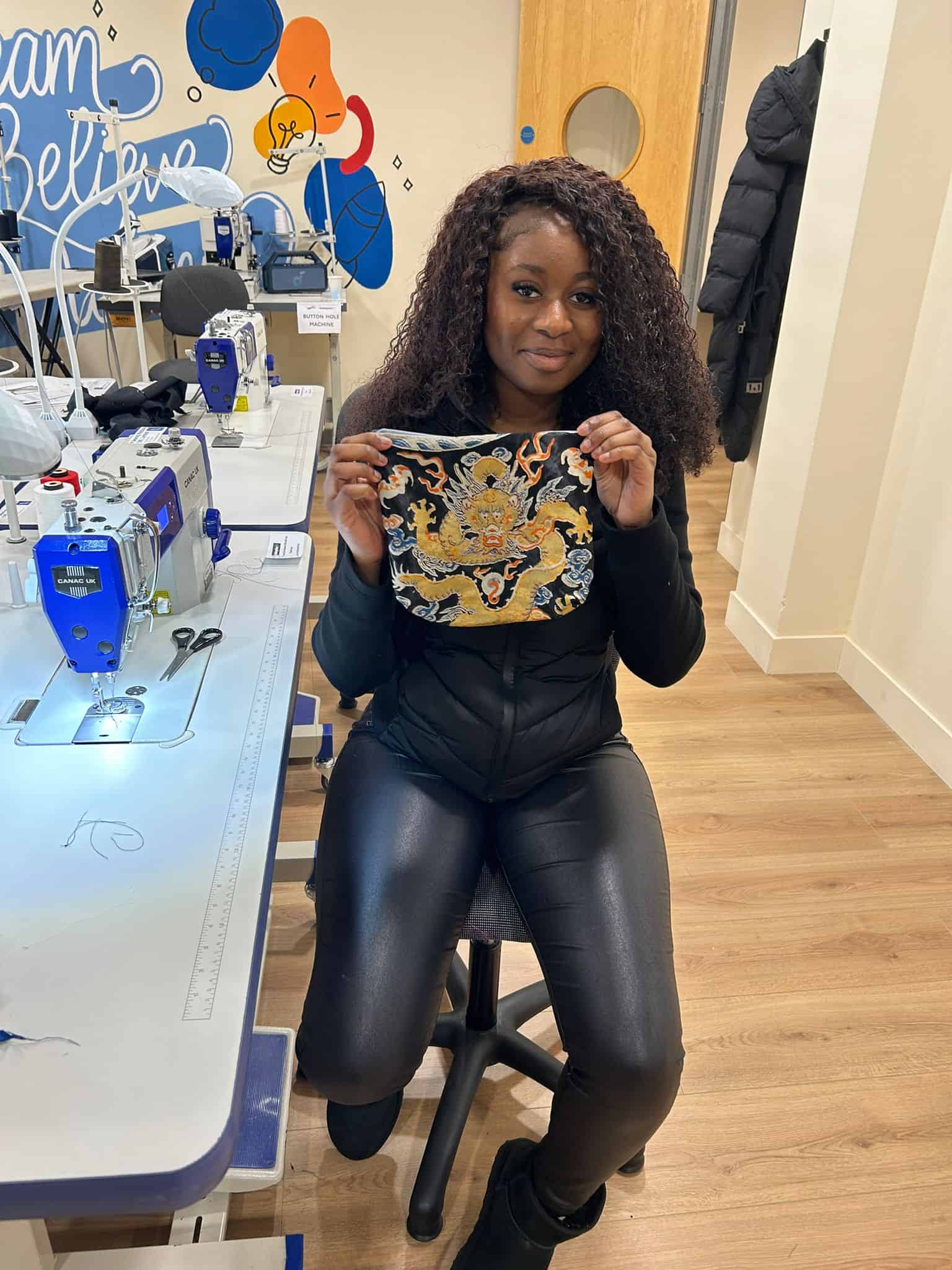 Woman holding embroidered fabric in sewing workshop at C4CWB.